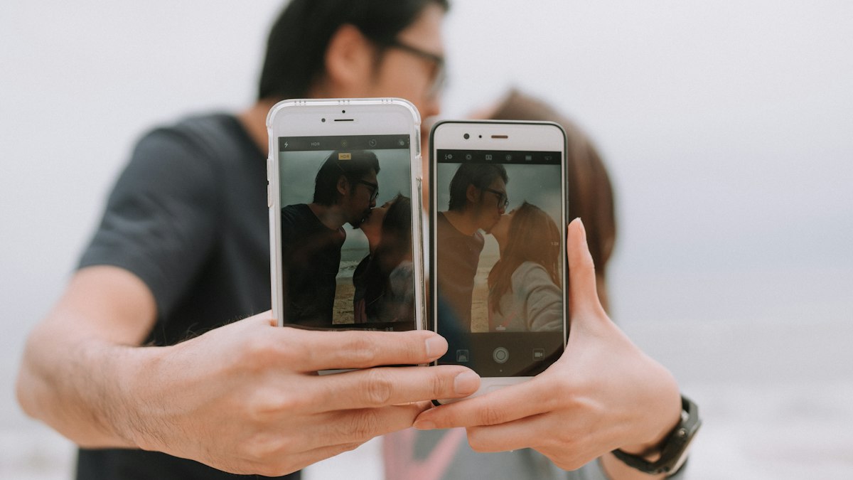 Paar vergleicht zwei Smartphones nebeneinander